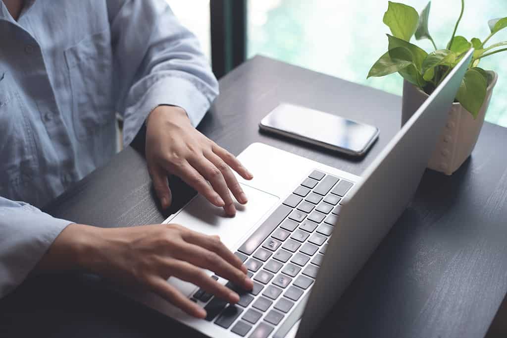 Close up of business woman hands typing on laptop computer, searching and surfing the internet on office desk, online working, telecommuting, freelancer at work concept